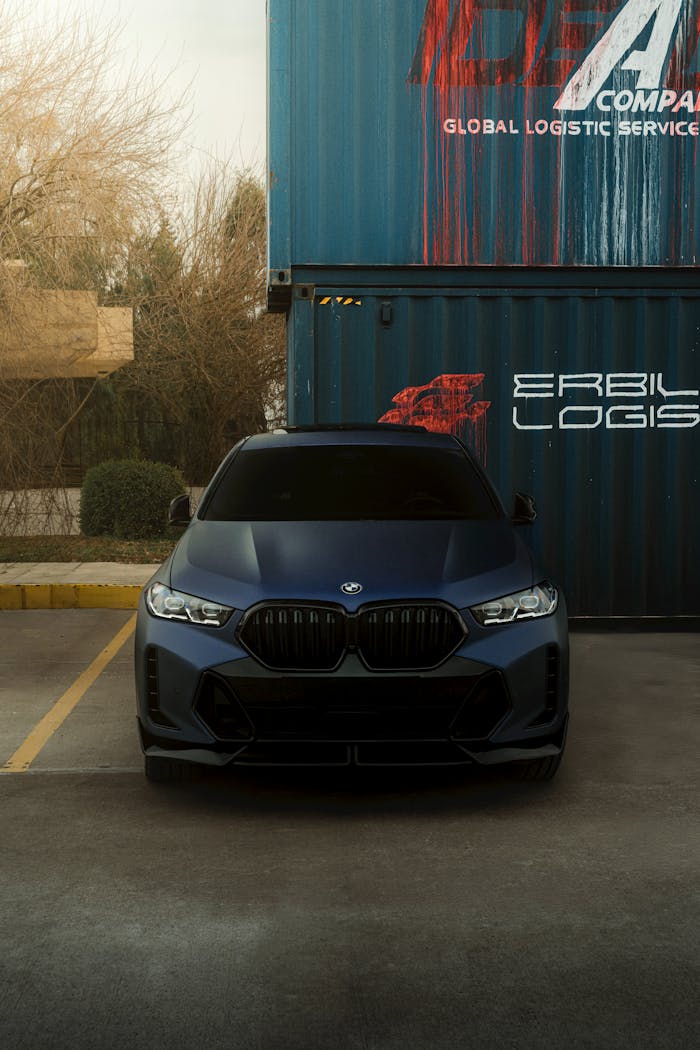 A sleek luxury car parked in front of an Erbil Logist shipping container in Erbil, Iraq.